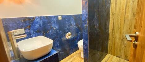 A bathroom with a white sink, a toilet, and a glass-enclosed shower area.