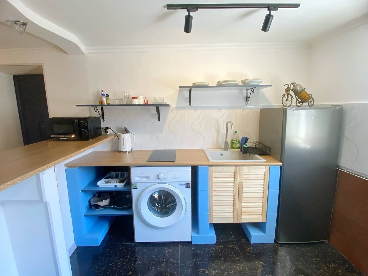 Una cocina compacta con lavadora, refrigerador y microondas.