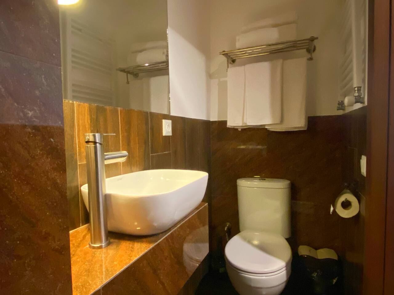 A bathroom with a large vessel sink, a toilet, and a towel rack.