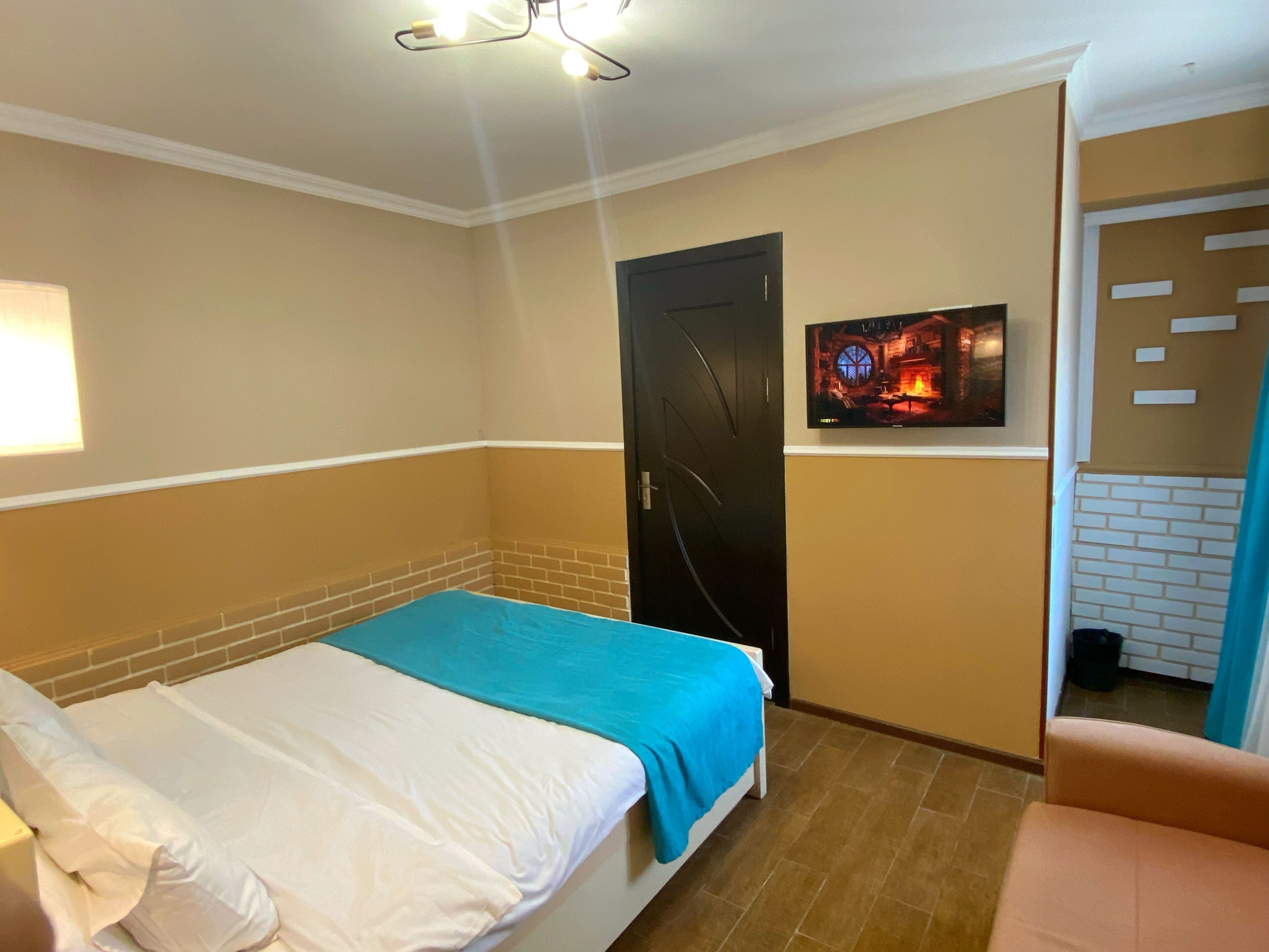 A hotel room with a bed, a TV mounted on the wall, and a door.