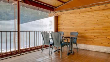 A wooden-paneled room with a balcony, featuring a table and chairs.