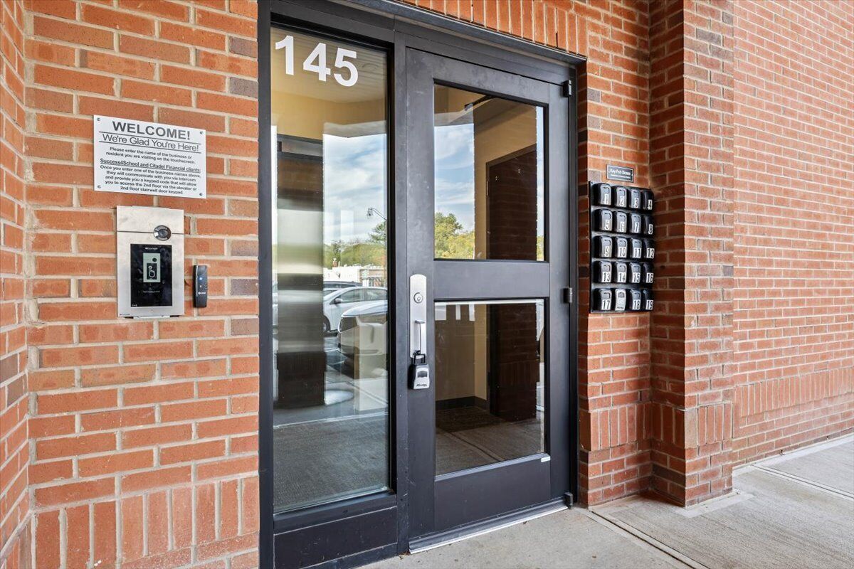 Un bâtiment en briques avec une porte noire portant le numéro « 145 » et une pancarte indiquant « Bienvenue ».