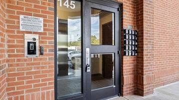 Un bâtiment en briques avec une porte noire portant le numéro « 145 » et une pancarte indiquant « Bienvenue ».