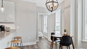 Una cocina moderna con encimera de granito, taburetes de madera y un comedor con mesa y sillas.