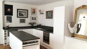 Una cocina moderna con armarios blancos, encimera negra y horno integrado.