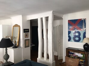 Una sala de estar con un sofá azul, una lámpara, un espejo y una estantería.