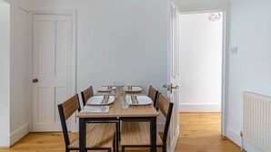 A dining area with a wooden table set for four, surrounded by chairs. - Modern Simplicity 10mins from Westfield, Stratford - Pass the Keys (London)