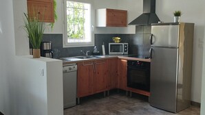 A compact kitchen with wooden cabinets, a stainless steel refrigerator, a microwave, and a dishwasher.