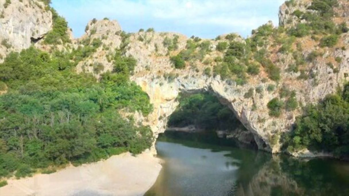 Formación rocosa natural con una abertura parecida a una cueva, rodeada de vegetación.