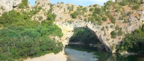 Formación rocosa natural con una abertura parecida a una cueva, rodeada de vegetación.