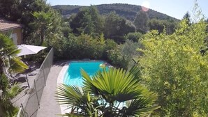 A swimming pool surrounded by lush greenery and a mountainous backdrop.