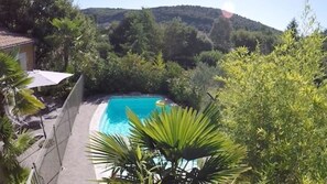 Ein Schwimmbecken, umgeben von üppiger Vegetation und einer Bergkulisse.