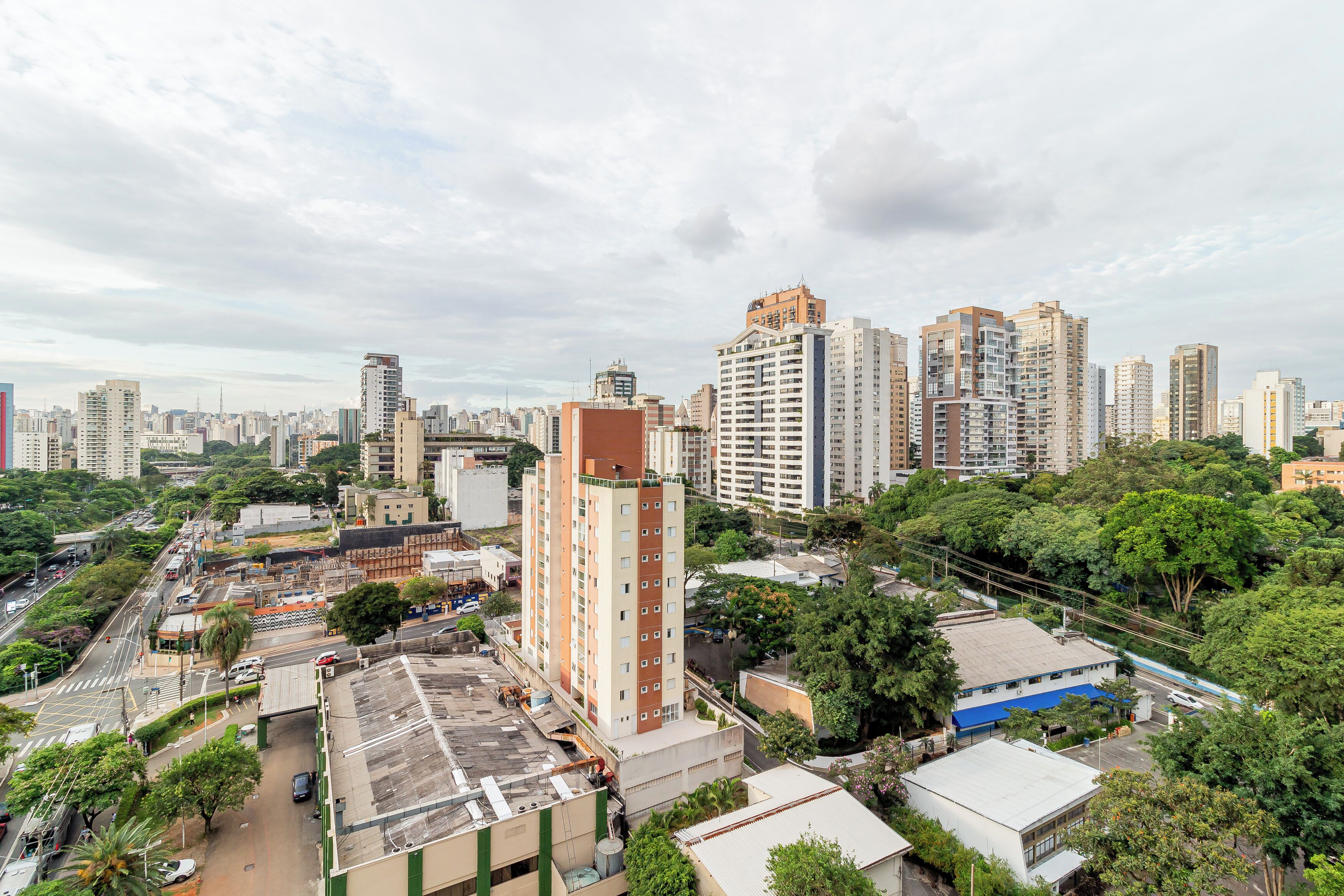 A high-rise building with a modern design, surrounded by other tall buildings and greenery.