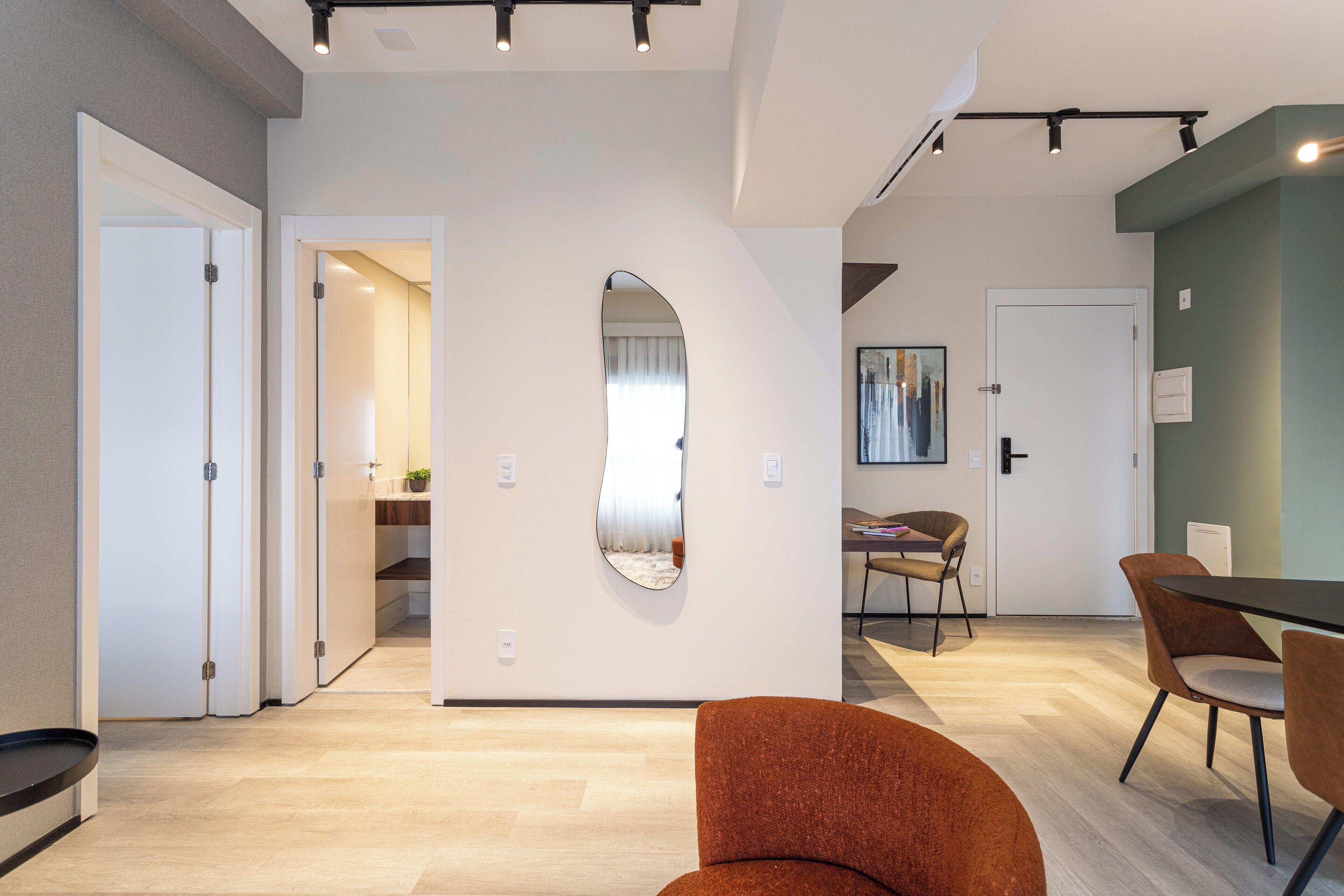 A modern interior with a dining area, a large mirror, and a hallway leading to another room.