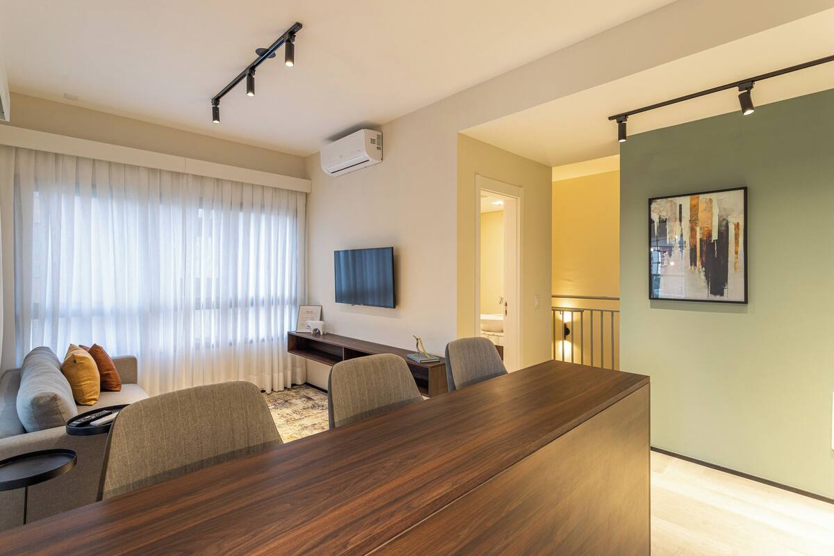 A modern living room with a wooden dining table, a sofa, and a TV.