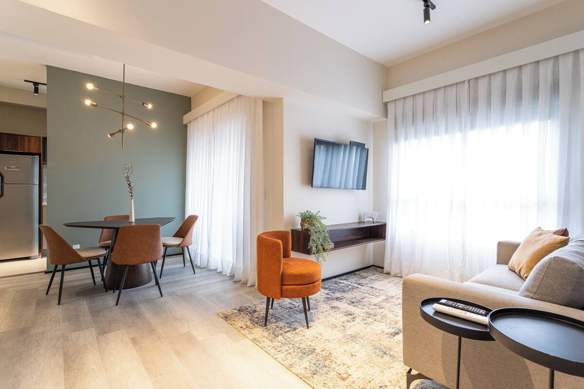 A modern living room with a sofa, a coffee table, and a dining area with chairs and a table.