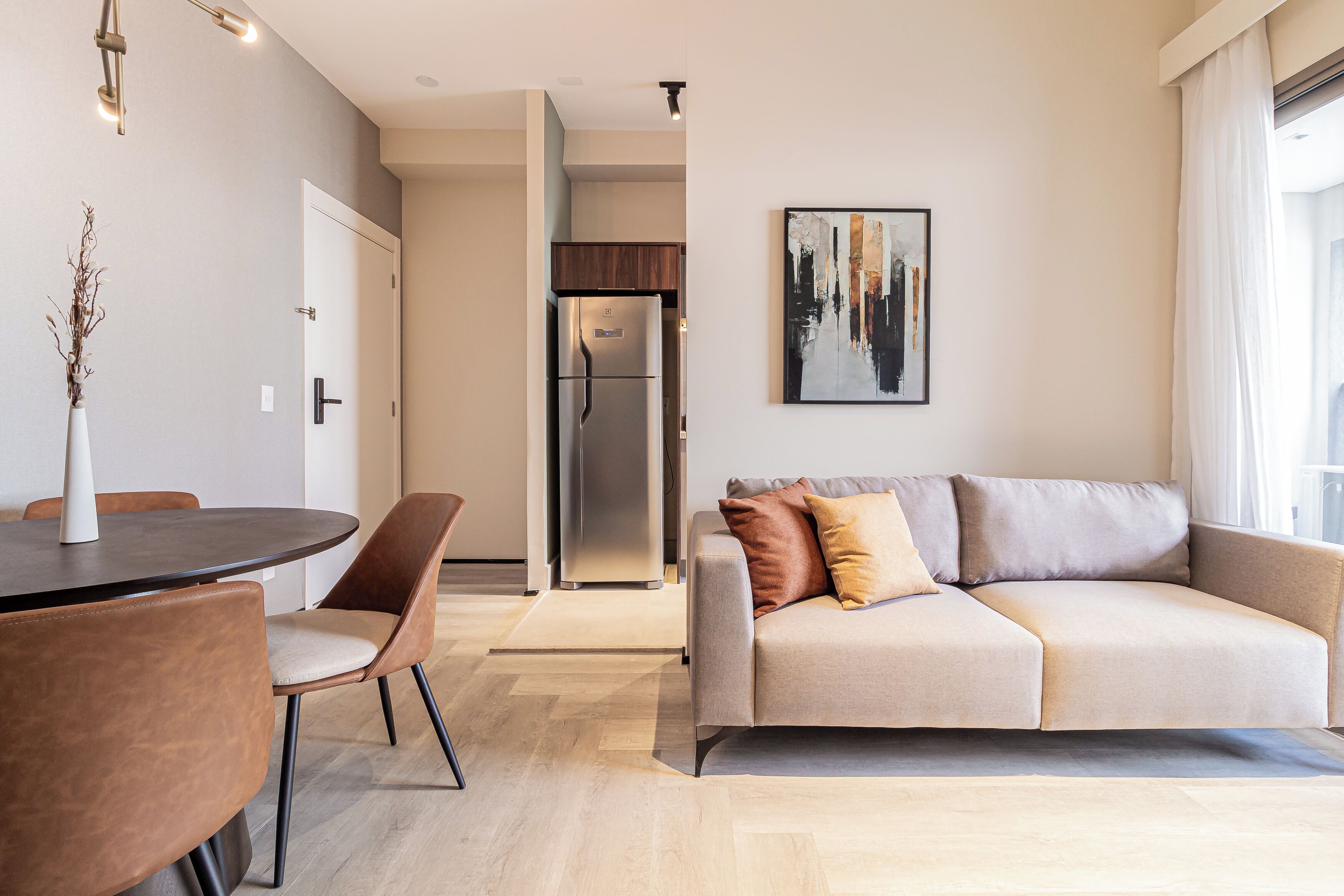 Un salon moderne comprenant un canapé, des fauteuils, une table à manger et un réfrigérateur.
