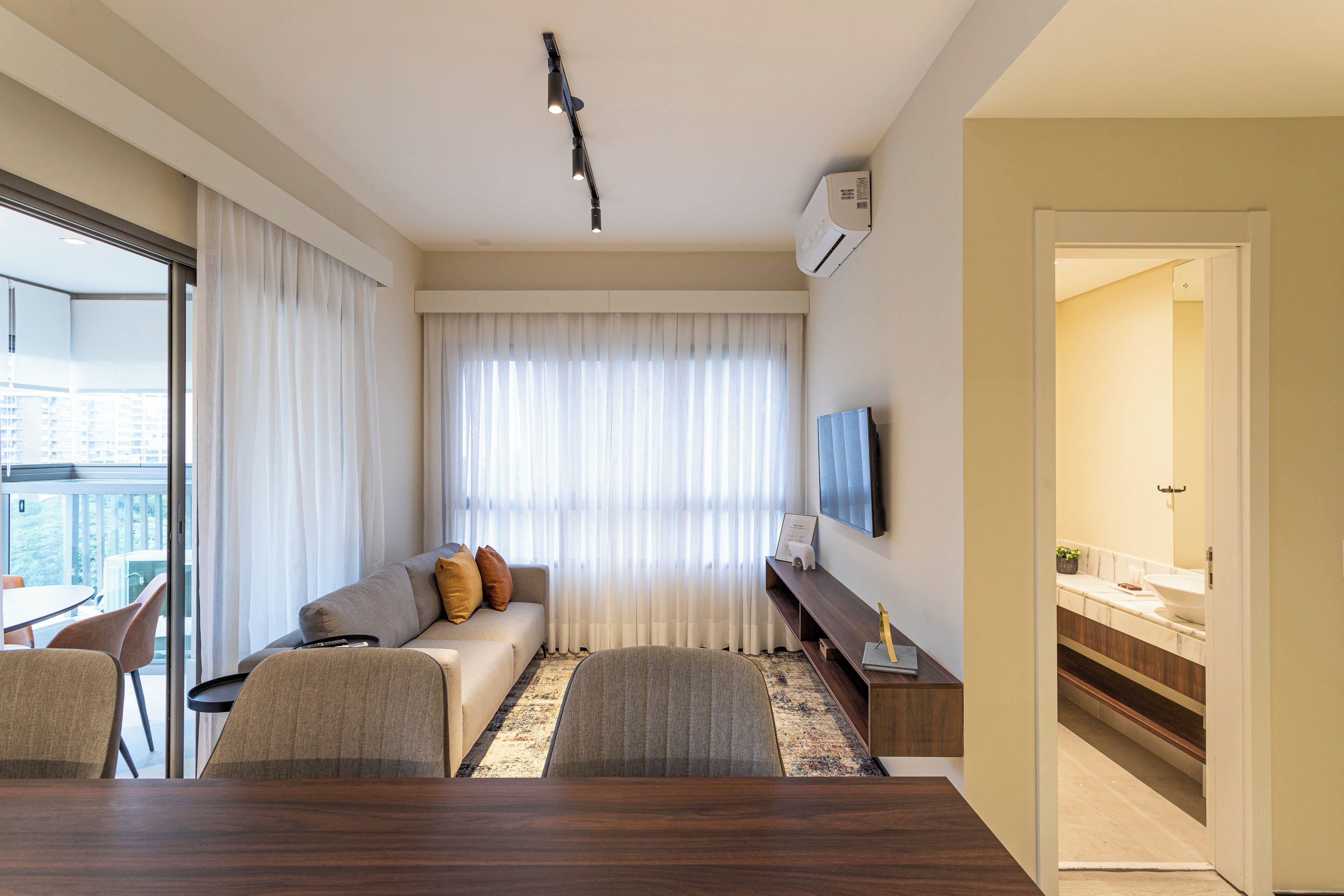 Una sala de estar moderna con un sofá, una mesa de comedor y un televisor montado en la pared.