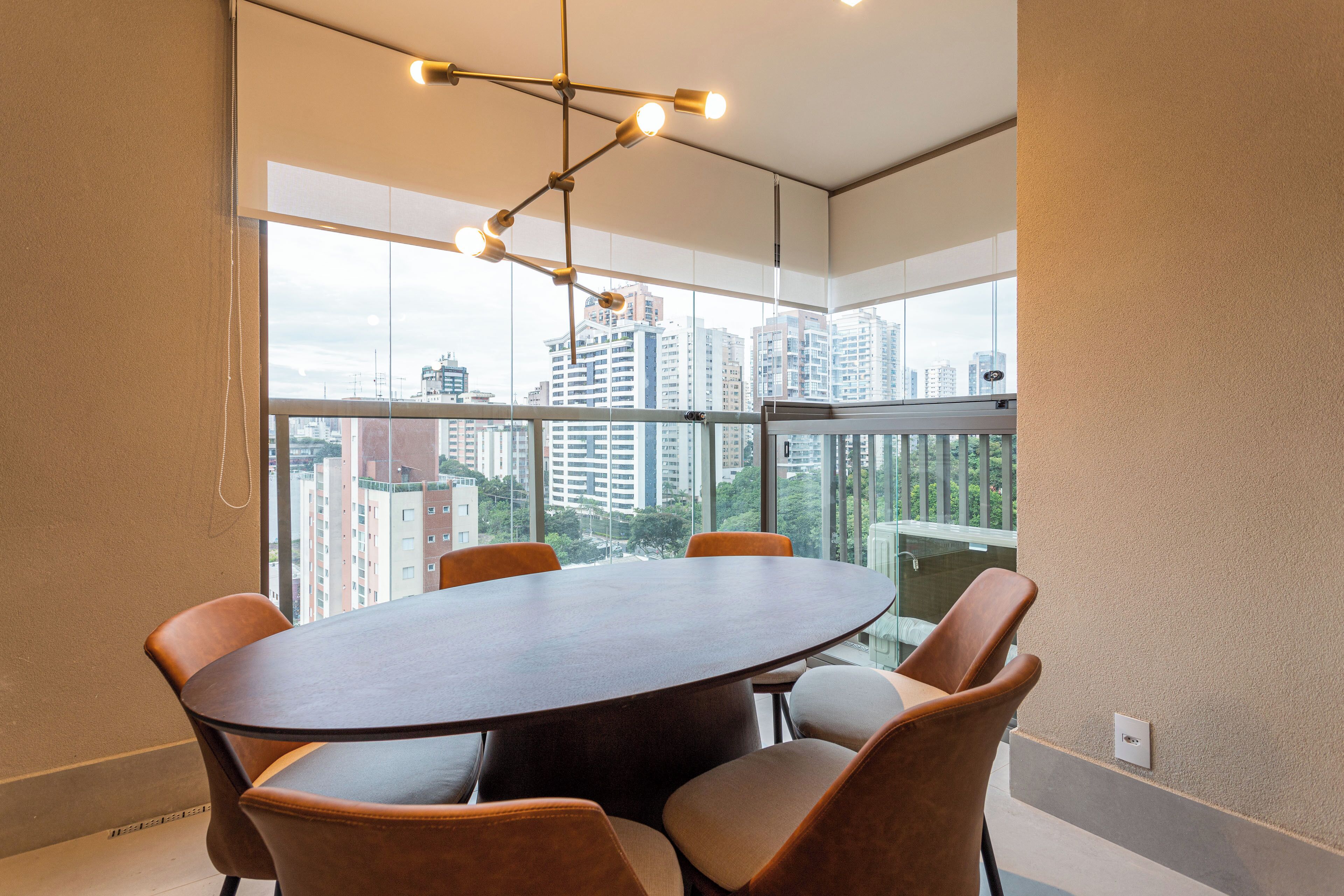 Una sala conferenze con un tavolo rotondo e sei sedie, ampie finestre con vista sulla città e un lampadario moderno.