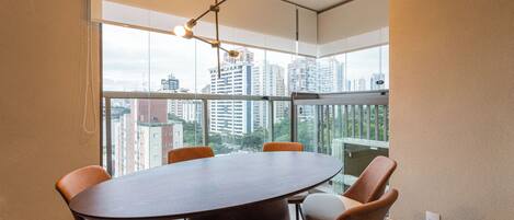 Una sala conferenze con un tavolo rotondo e sei sedie, ampie finestre con vista sulla città e un lampadario moderno.