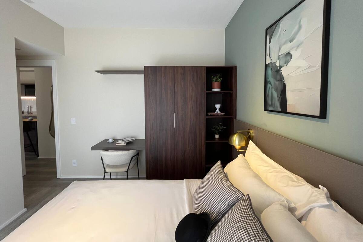 A modern bedroom with a bed, a desk, a wardrobe, and a bookshelf.