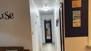 Un couloir avec un canapé beige, un petit banc en bois et une porte au fond.