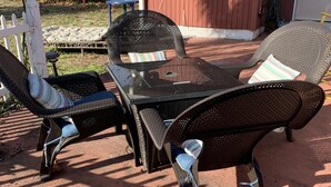 Une terrasse dotée de meubles en osier, notamment deux chaises et une table.