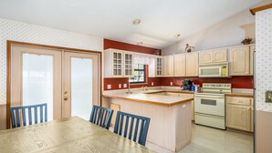 A kitchen with wooden cabinets, a central island, and a dining table with chairs. - Private Lake View House Rental close to wonderful Big Bass Grill restaurant  (Lake Panasoffkee)