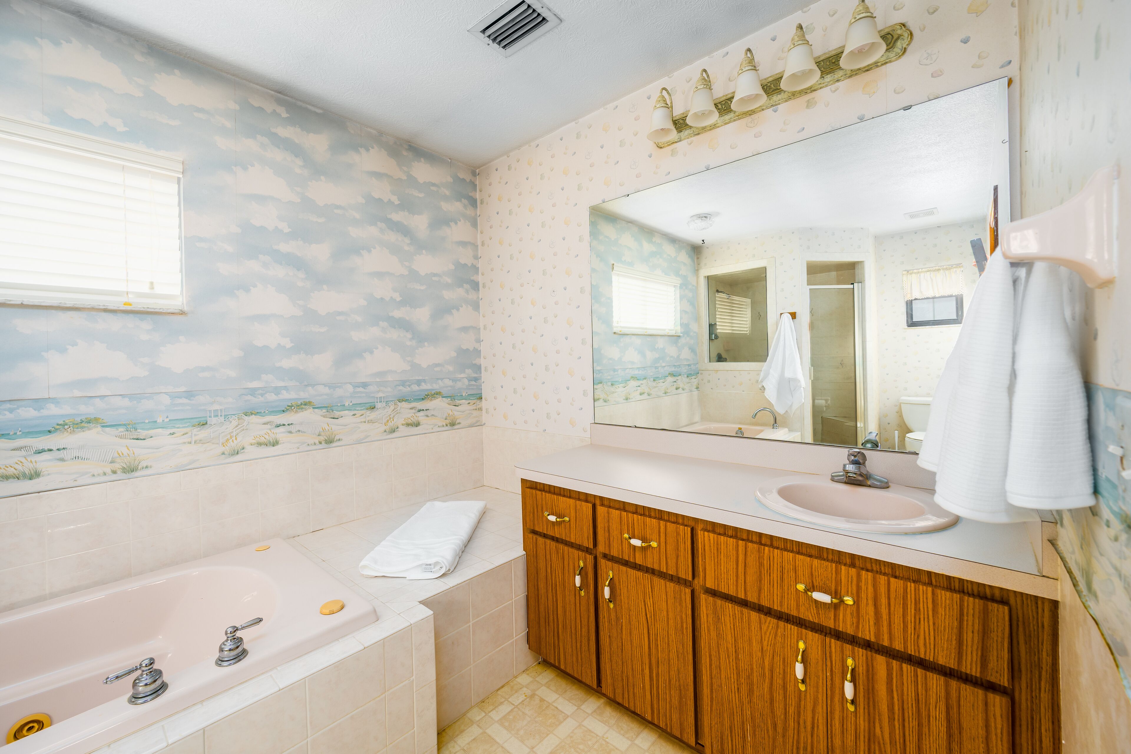 A bathroom with a bathtub, vanity, and a large mirror.
