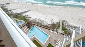 A beach view from a hotel balcony with a swimming pool and lounge chairs. - "Seaside Bliss: Beachfront Condo with Stunning Ocean-View Balcony!" (Orange Beach)