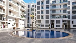 A modern apartment building with a central courtyard featuring a swimming pool.