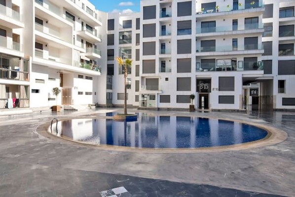 Un moderno edificio de apartamentos con un patio central que tiene una piscina.
