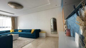 A modern living room with a blue sofa, a coffee table, and a large mirror.