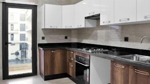 A modern kitchen with white cabinets, a black countertop, and a stainless steel sink.