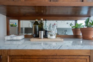 A kitchen counter with various bottles, a cutting board, and potted plants. - Trastevere lovely and cozy apartment (Roma)