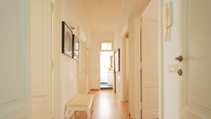 A hallway with white doors, a bench, and framed pictures on the walls.