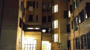 A courtyard with multiple floors of residential buildings, outdoor seating, and a central illuminated entrance.