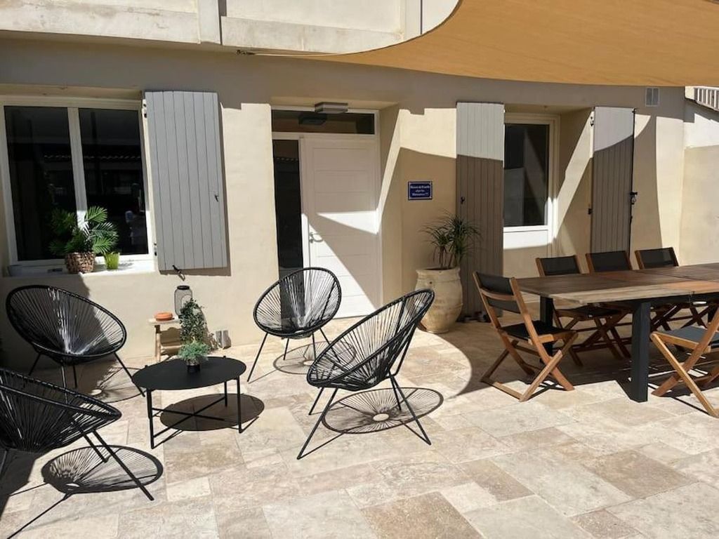 An outdoor seating area with chairs and a table, a potted plant, and a building entrance.