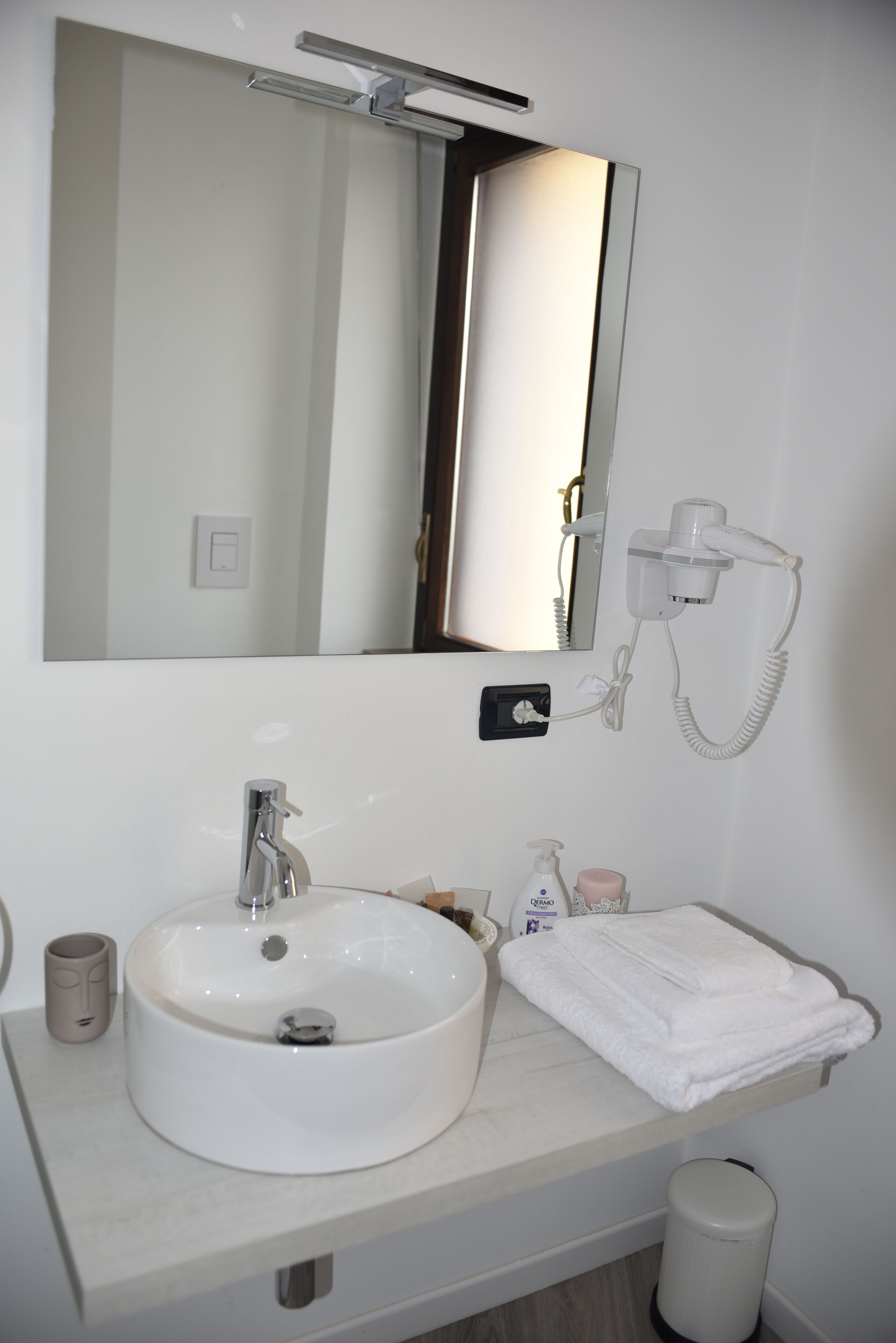 A bathroom with a white sink, a mirror, a hairdryer, and a towel.