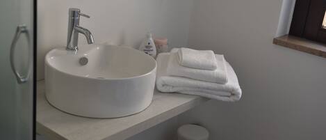 A bathroom with a white sink, a towel rack, and a trash bin.