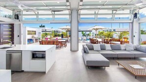 Una cucina moderna con lavastoviglie e microonde integrati, una zona pranzo con posti a sedere all'aperto e un'ampia finestra con vista su una piscina e sul verde.