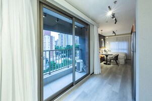 A modern hotel room with a balcony, a bed, a small table, and a chair.