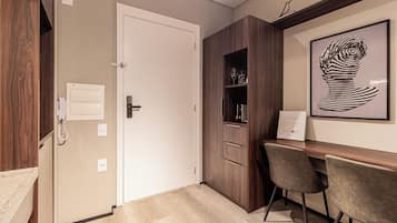 A modern room with a wooden desk, two chairs, a white door, and a framed artwork on the wall.