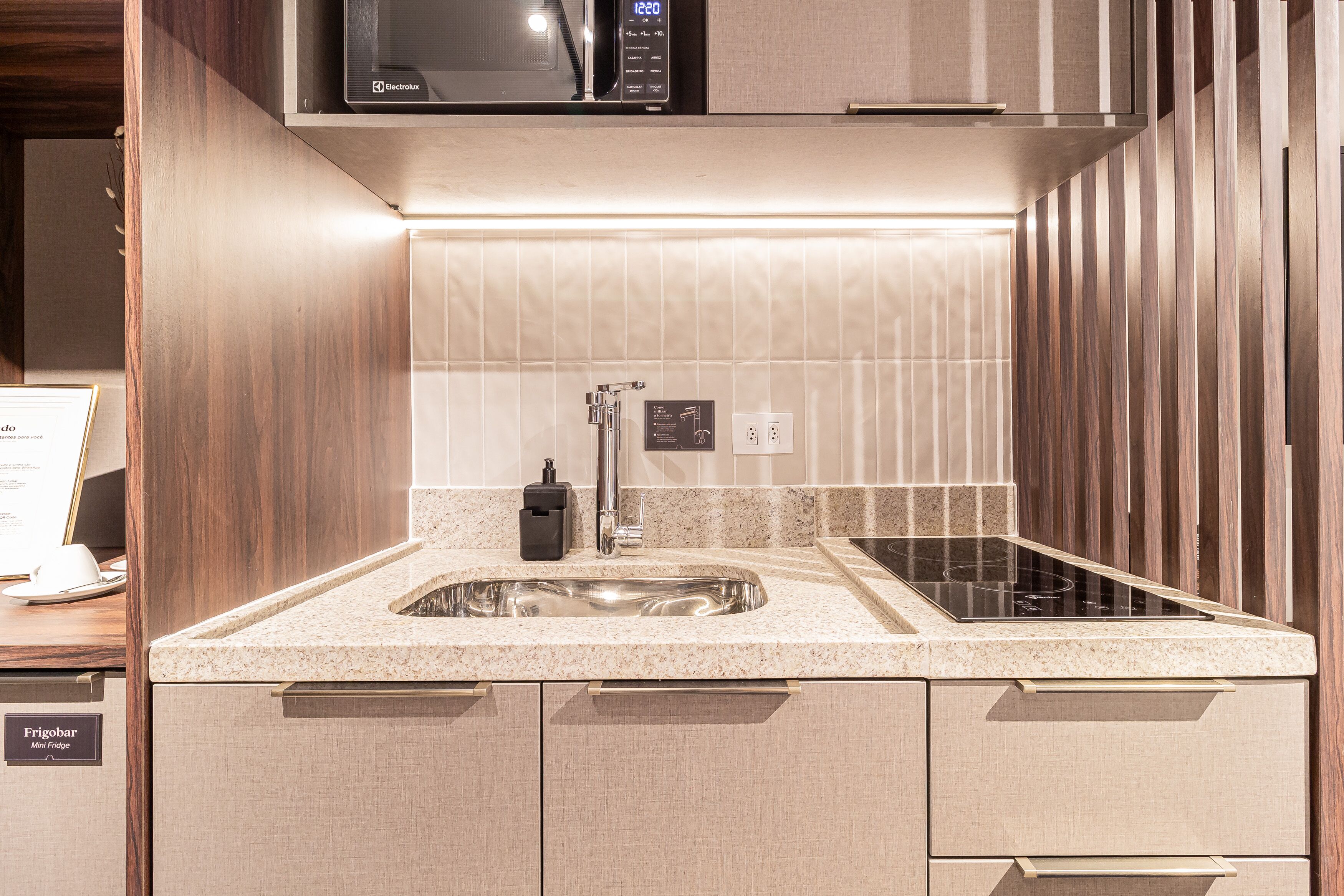 A modern kitchen with a built-in microwave, a stainless steel sink, and a black faucet.
