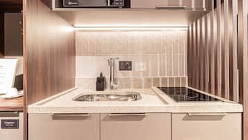 A modern kitchen with a built-in microwave, a stainless steel sink, and a black faucet.