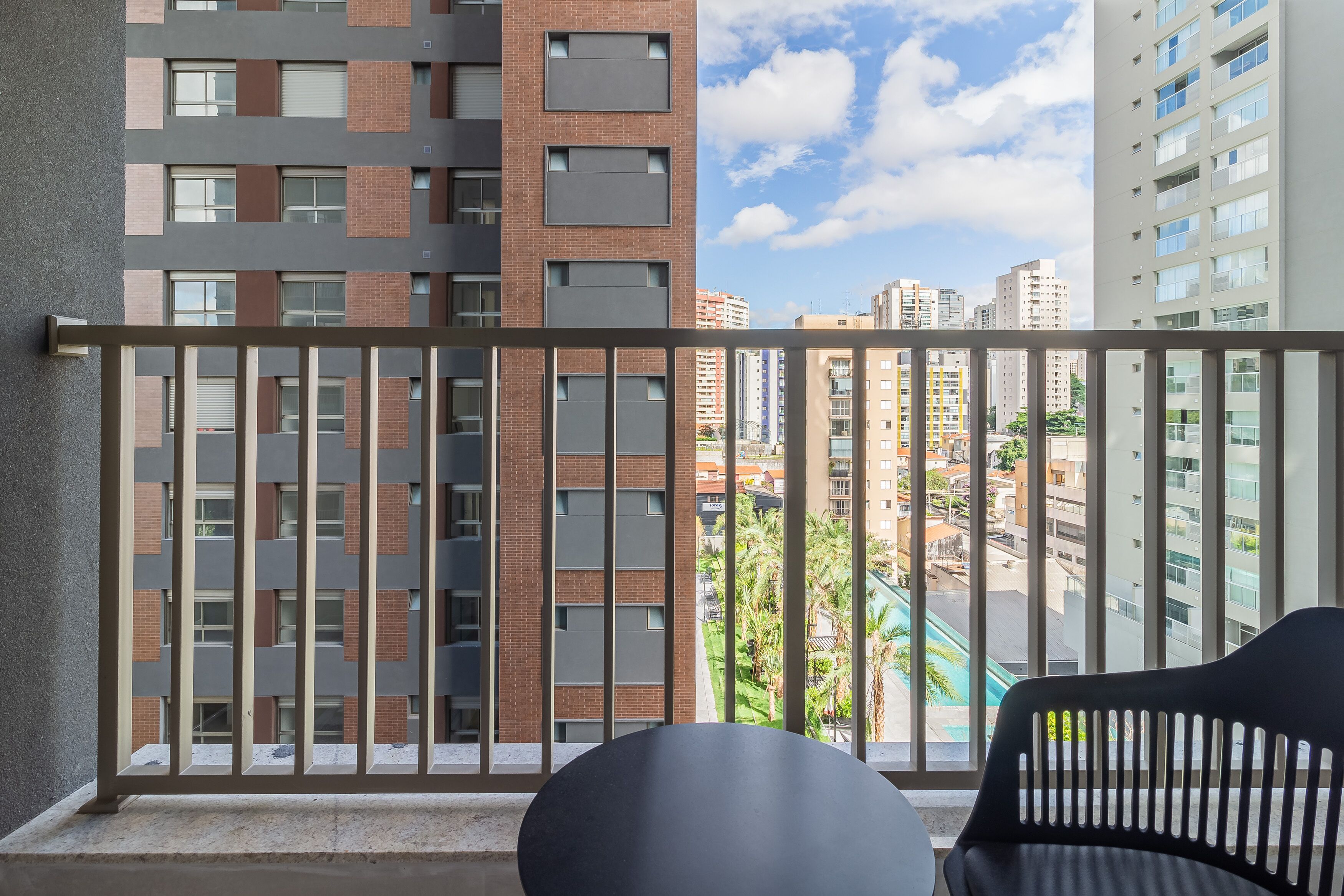 A balcony with a view of a cityscape, including a pool and buildings.