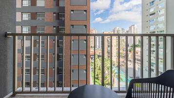 A balcony with a view of a cityscape, including a pool and buildings.