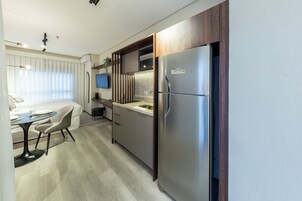 A compact kitchen with a built-in refrigerator, a dining area with a table and chairs, and a small countertop with a sink.