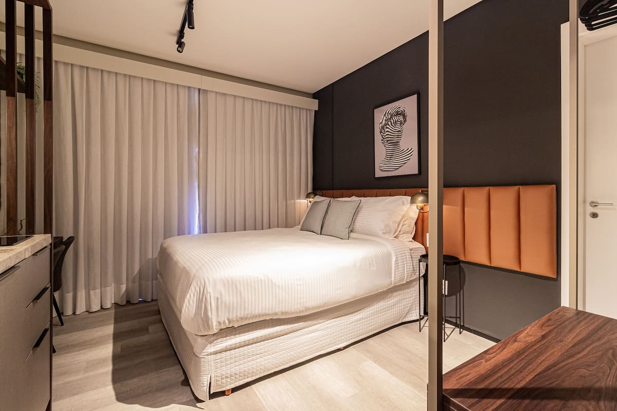 A modern bedroom with a large bed, a desk, and a chair.
