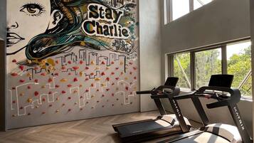 A modern gym with a mural featuring a face and the text "Stay Charlie."
